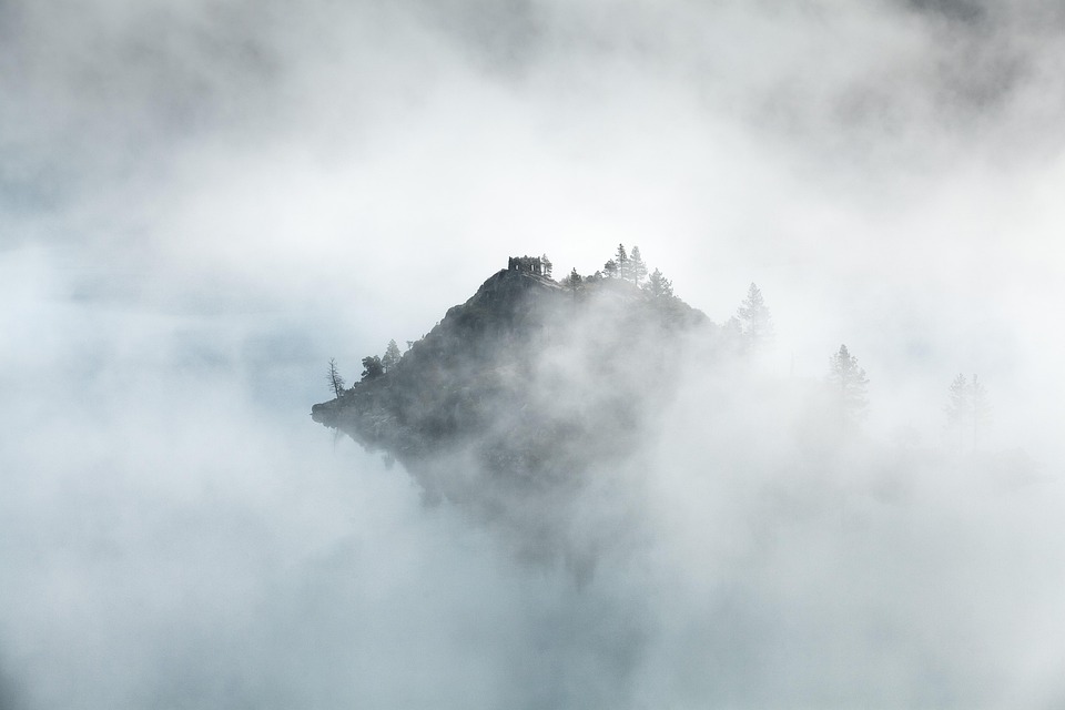 Mist-covered mountains with peaks partially obscured by thick fog, creating a serene and mysterious atmosphere.